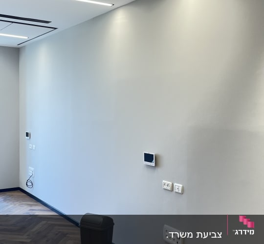 קיר צבוע עם רצפת עץ ופח אשפה